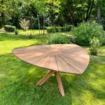 Tuintafel gemaakt van massief teakhout, de tafel heeft een driehoekig blad met een houten kruis poot.